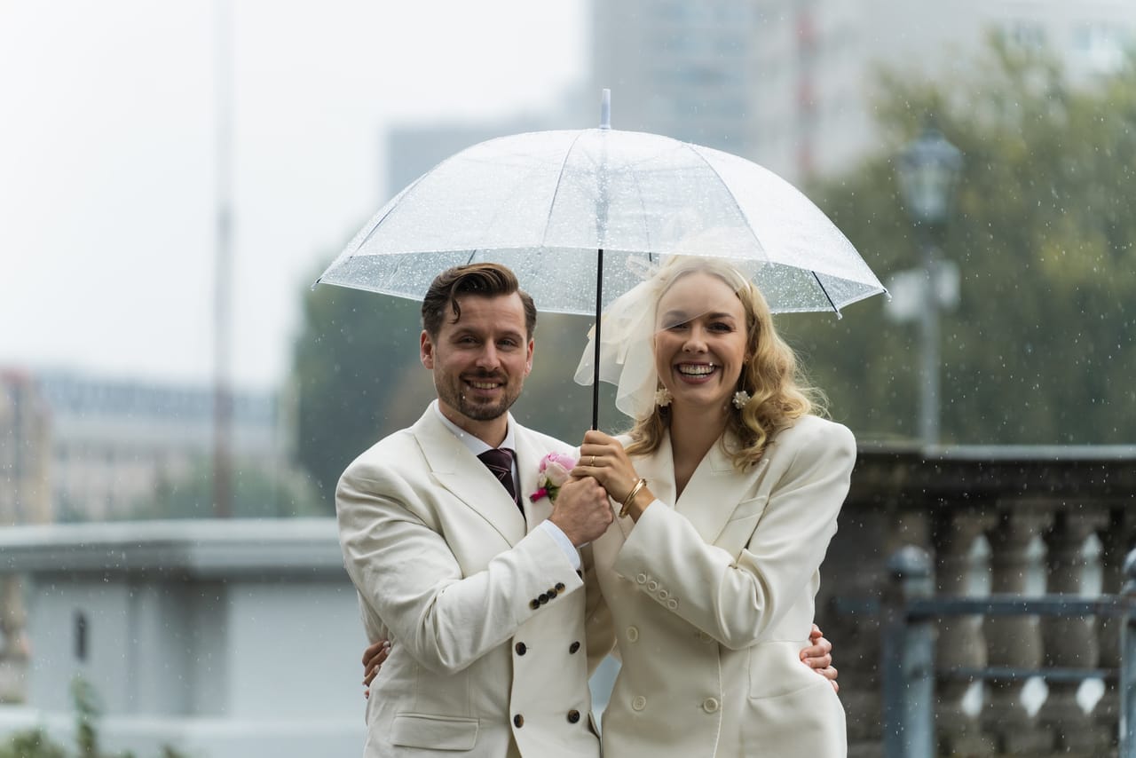 Anna und Marco lachen unter dem Regenschirm